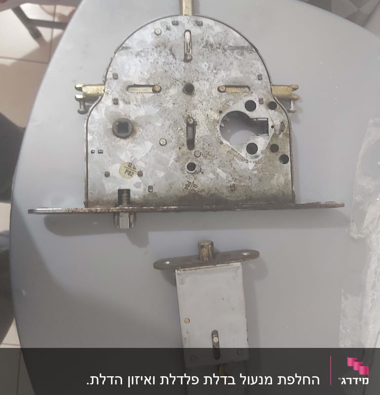 מנעול מתכת ישן עם חלקים חשופים על שולחן אפור